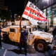 A protester waves a DC flag with Black Lives Matter spray painted on it next to a DC National Guard Humvee as protesters march through the streets during a demonstration over the death of George Floyd, who died in police custody, on June 2, 2020.