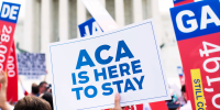 Affordable Care Act supporters wave signs outside the Supreme Court.